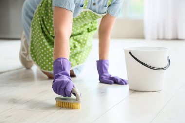 Ev hanımı mutfakta fırçayla yerleri temizler, yakın plan.