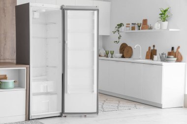 Boş buzdolabı ve tezgahları olan modern mutfağın içi.