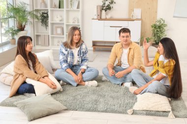 Grup terapisinde halıda konuşan genç bir kadın.
