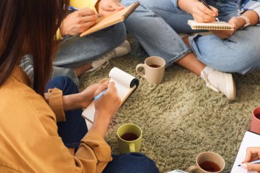 Grup terapi seansında deftere yazan genç bir kadın. Yakın çekim.