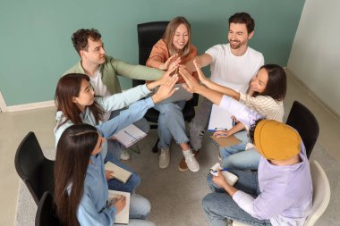 Grup terapi seansında el ele tutuşan gençler