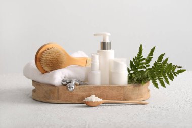 Masaj masalı tepsi vücut fırçası ve beyaz arka planda kozmetik ürünler şişeleri, yakın plan