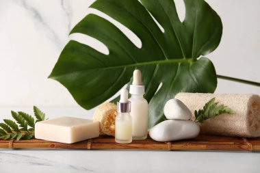 Bambu tepsisiyle spa bileşimi, mermer arka planda taşlar ve kozmetik ürünler şişeleri, yakın plan