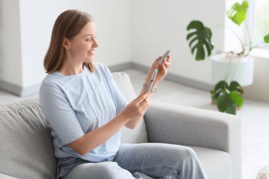 Evde koltukta oturan tüp bebek hormonu şırıngalı genç bir kadın.