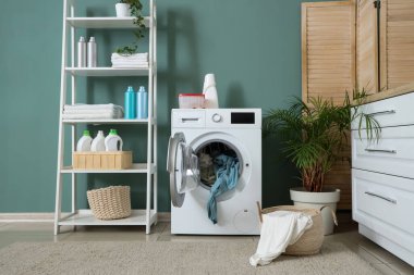 Çamaşır makinesi, raf ünitesi ve katlama ekranlı çamaşır odasının içi.