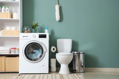 Çamaşır makinesi, klozet ve raf ünitesi olan bir çamaşırhane.