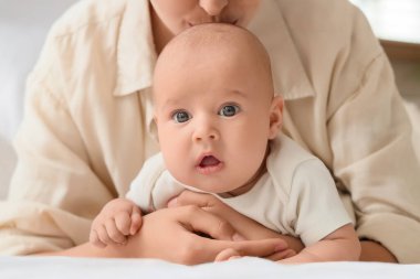 Anne küçük bebeğiyle yatak odasında uzanıyor, yakın plan. Tüp bebek konsepti