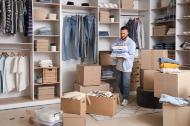 Giysileri katlanmış ve soyunma odasında dolapları olan genç bir adam.