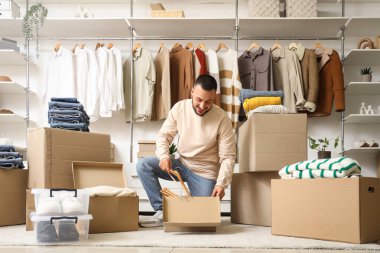 Genç adam soyunma odasındaki elbise dolabından askıyı alıyor.