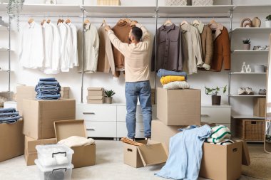 Dolabında asılı giysileri olan genç bir adam.