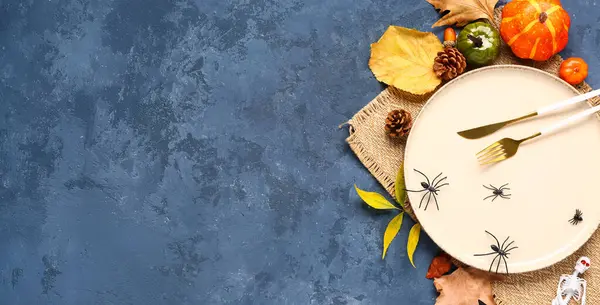 Mavi grunge arka planda balkabakları, örümcekler ve sonbahar yapraklarıyla Cadılar Bayramı sofrası