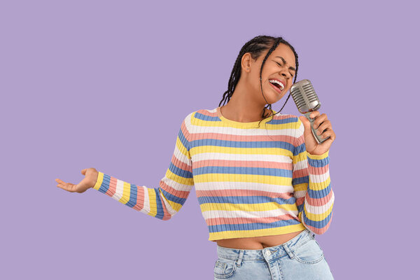 Молодая афроамериканка с микрофоном поет на фоне сирени