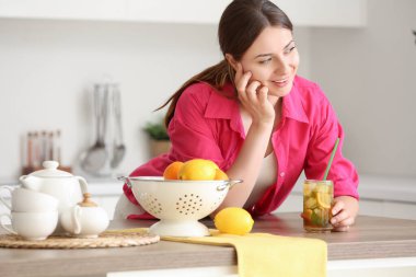 Mutfaktaki masada buzlu çay içen genç bir kadın.