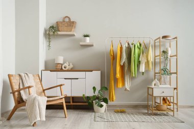 Elbise askısı, koltuk ve klozeti olan bir soyunma odası.