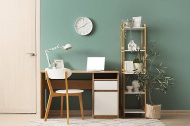 Ofisin içinde duvar saati, işyeri ve raf ünitesi var.