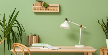 Kitaplar, lamba ve okaliptüs dallarıyla dolu bir masa.