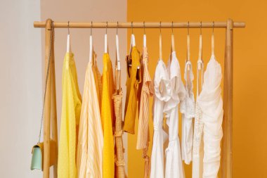 Sarı arka planda askıda asılı kadın giysileri