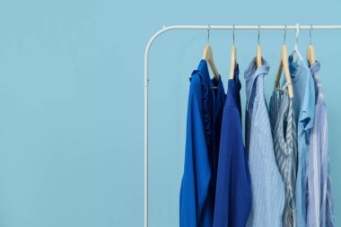 Mavi duvarın yanında kadın kıyafetleriyle dizilin.