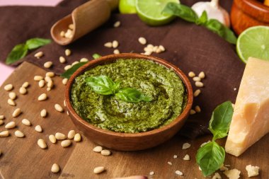 Lezzetli pesto soslu ahşap tahta, çam fıstığı, fesleğen yaprağı ve peynir, yakın plan.