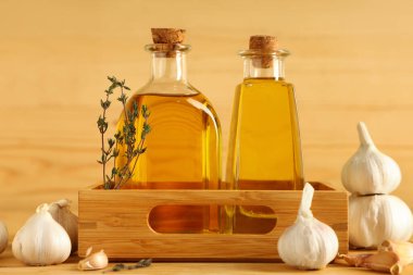 Tahta zemin üzerinde kekik olan bir şişe taze sarımsak yağı.