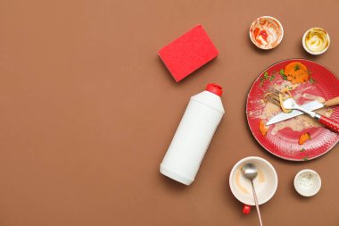 Kirli bulaşıklar, deterjan ve kahverengi arka planda sünger. Üst görünüm
