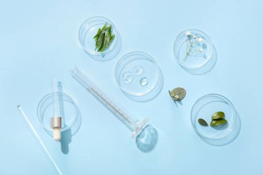 Açık mavi arka planda doğal kozmetik ürünleri örnekleri içeren petri kapları