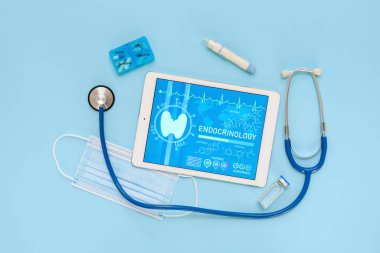 Steteskoplu tablet bilgisayar ve mavi arka planda tükenmez kalem. Endokrinoloji kavramı