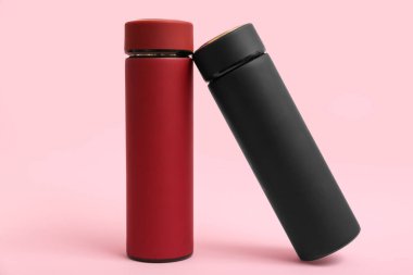 Pembe arka planda farklı modern termoslar
