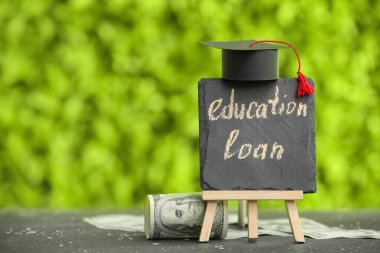 Açık havada yazı tahtasıyla birlikte kredi, mezuniyet şapkası ve dolar banknotları.