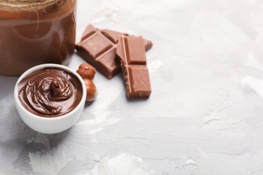 Bir kase lezzetli çikolata, arkaplanda fındık var.