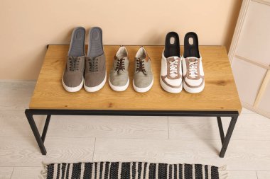 Koridordaki bej duvarın yanındaki bankta ortopedik tabanlı spor ayakkabılar.