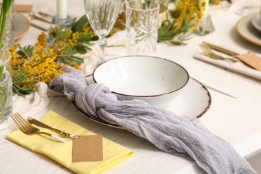 Restoranda güzel çiçekli ve altın çatal bıçaklı şık bir masa, yakın plan.