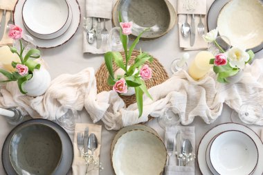 Lokantada güzel lale çiçekleri, mumlar ve temiz tabaklar olan şık bir masa.