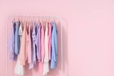 Pembe duvara karşı şık kadın kıyafetleriyle dizilin.