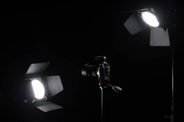 Siyah arka planda stüdyo ışığı olan fotoğraf makinesi.
