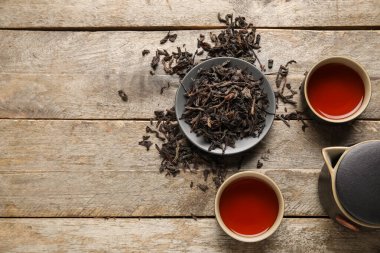 Sıcak siyah çay fincanları ve ahşap arka planda kuru yapraklar.