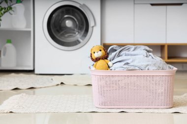 Odada halı üstünde oyuncak aslan olan çamaşır sepeti.