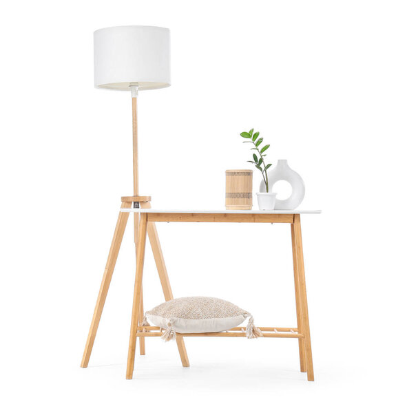 Wooden stand with plant, pillow and lamp on white background