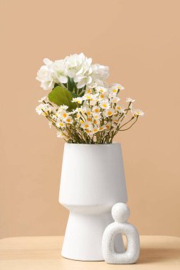 Masada bej arka planda suni çiçekli vazo