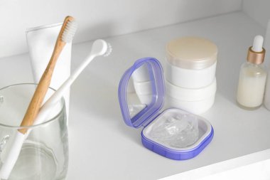 Dolabın rafında oklüzyon bandı ve banyo aksesuarları olan kutu, yakın plan.