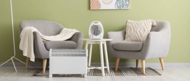 Modern elektrikli ısıtıcıları ve gri koltukları olan şık bir oturma odası.