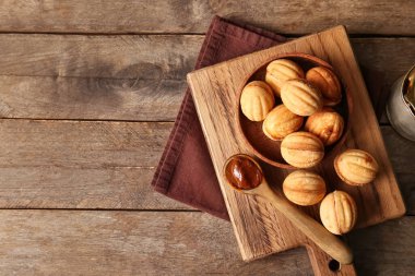 Lezzetli ceviz şekilli kurabiye ve ahşap zemin üzerinde kaynamış süt kesilmiş tahta.