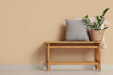 Odada bej duvarın yanında minderleri ve çiçekleri olan bir bank.