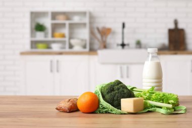 Mutfaktaki ahşap masanın üzerinde farklı taze ürünler olan ip torbası.