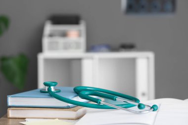 Klinikte tıp öğrencilerinin masasına not defterleriyle steteskop, yakın plan.