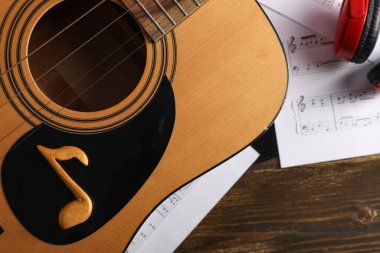 Gitar, işaret ve nota kağıtları ahşap masada, yakın plan.