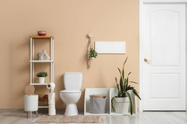 Tuvaletin içinde klozet, raf ünitesi ve bitkiler var.