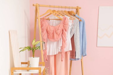 Soyunma odasındaki pembe duvarın yanında kadın giysileriyle doldur.