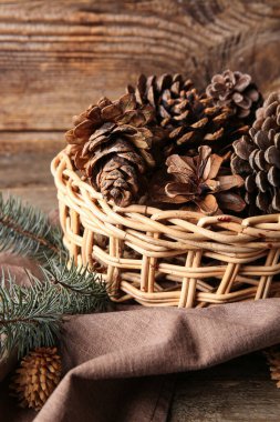 Çam kozalaklı hasır kase ve ahşap arka planda köknar dalları