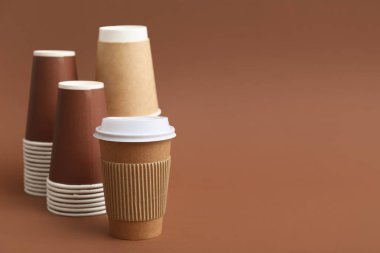 Kahverengi arka planda tek kullanımlık kahve fincanları